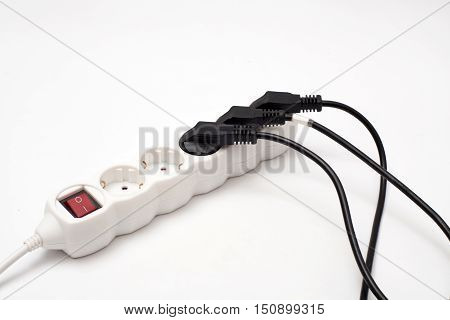 Many plugs plugged into electric power bar on white
