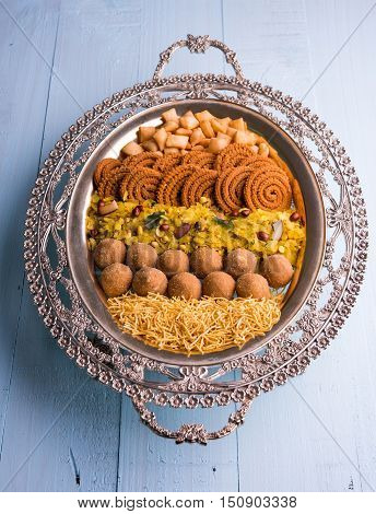Plate full of indian festival food or diwali food or snacks like laddu, chivda, chakali or murukku, sev and shankar pale, sweet and salty snack food