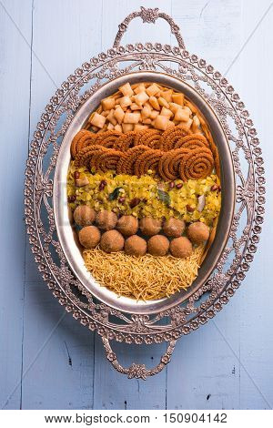 Plate full of indian festival food or diwali food or snacks like laddu, chivda, chakali or murukku, sev and shankar pale, sweet and salty snack food