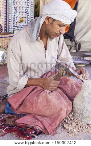 Badajoz Spain - September 24 2016: Artisan makes pieces for mosaic craftwork. He is shaping pieces from glazed tiles