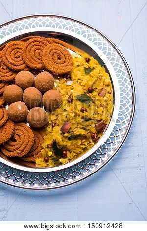 Plate full of indian festival food or diwali food or snacks like laddu, chivda, chakali or murukku, sev and shankar pale, sweet and salty snack food