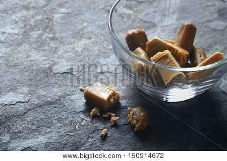 Toffee in the glass bowl on the stone table