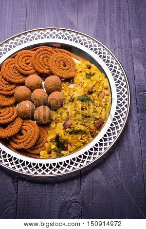 Plate full of indian festival food or diwali food or snacks like laddu, chivda, chakali or murukku, sev and shankar pale, sweet and salty snack food
