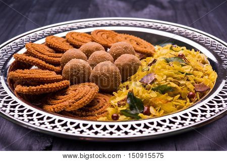 Plate full of indian festival food or diwali food or snacks like laddu, chivda, chakali or murukku, sev and shankar pale, sweet and salty snack food