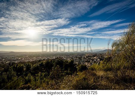 Panoramic view of the Alhambra, the city of Granada and the Vega of Granada at sunset under a cloudy sky
