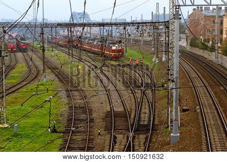 SAINT-PETERSBURG RUSSIA - Old locomotives RZD stand on railroad tracks of technical railway station - operational locomotive depot on autumn morning in fog. Workers in overalls serve rail journey. Transport infrastructure of Russian Railways St. Petersbur
