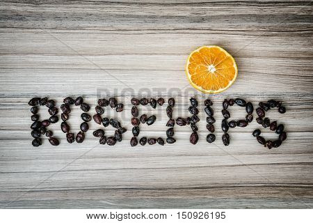 Title ROSEHIPS composited of the dried rosehips with slice of orange. Autumn theme. Food scene.