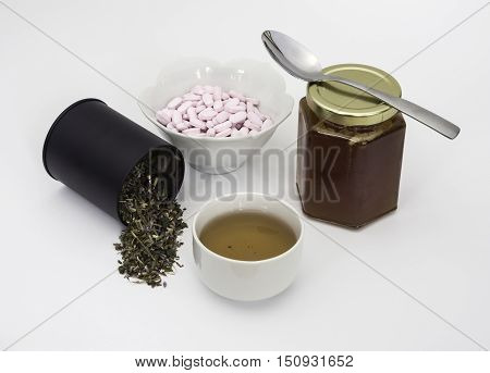 Green herb tulse with cup of tea Vitamin B12 tablets and jar of chestnut honey