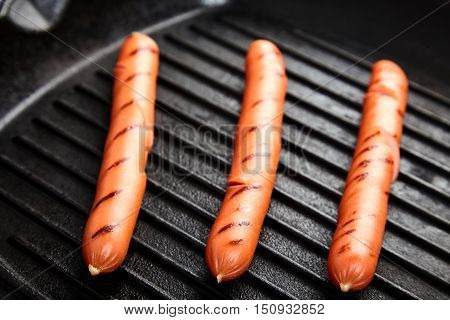 Close up of three hot Vienna sausages on the grill pan. Ingredients for making homemade hot dogs. Perfect lunch with easy dish. Fast food snack