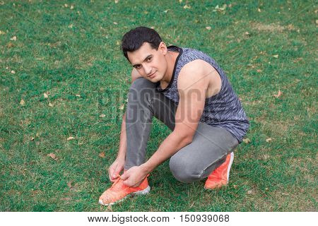 Young fitness man ties up bootlaces on his sport footwear outdoor