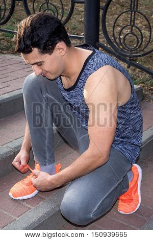 Young fitness man ties up bootlaces on his sport footwear outdoor