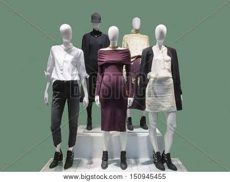 Five female mannequins dressed with fashionable modern clothes. Isolated on green background. No brand names or copyright objects.