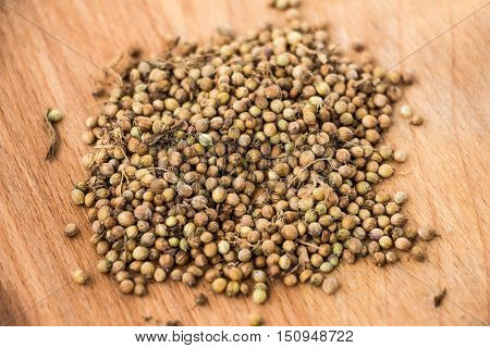 Handful of dryed coriander seeds on wood texture background