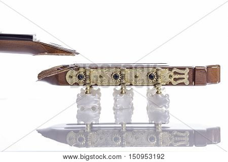 A broken classical acoustic guitar headstock that has snapped off from the neck and is awaiting repair. Isolated against a white background with reflection and copy space.
