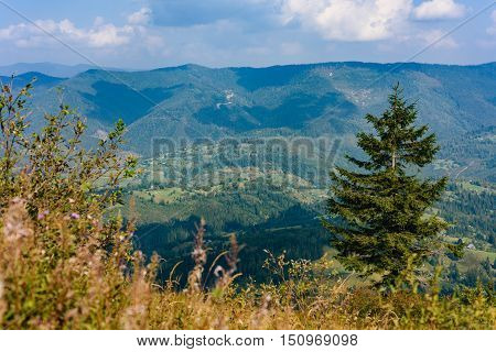 Top of the hill in Carpathian's. View to the village in mountains. Beautiful blue sky with clouds in the background. Summer time.