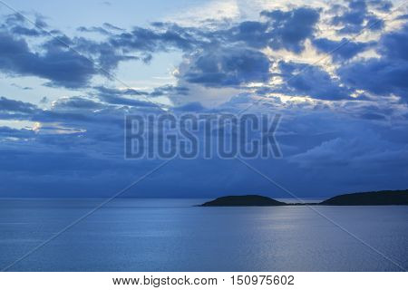 Moody gray storm clouds drift over calm Caribbean Sea and silhouette of tropical island of Isla Culebra
