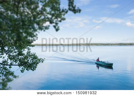 The boat floats on the lake in summer day. Tilf shift