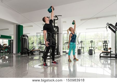 Fitness Couple Using Kettlebells Inside Gym