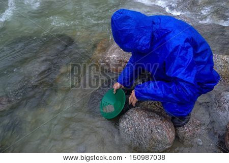 a man panning gold in a river with a sluice box