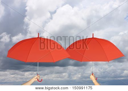 Two Red umbrella in hand and rain protectionconcept for management business idea on rain cloud background.