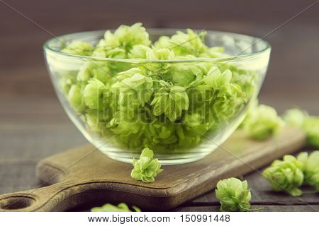 Close Up Of Green Ripe Hop Cones In A Glass Bowl Over Dark Rustic Wooden Background. Beer Production