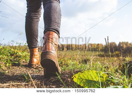 Female legs shod in Hiking boots on the forest background