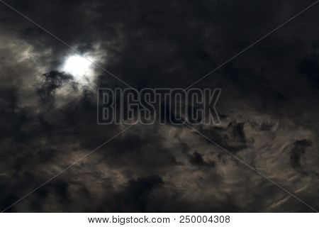Part Of The White Disk Of The Sun Behind Dark Storm Clouds,
