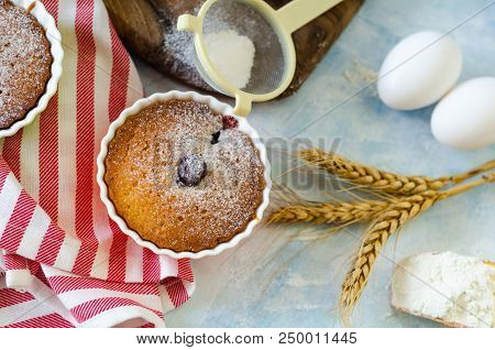 Cakes With Cerries On A Table In Small Porcelain Cups .there Are  Eggs, Flour, Wheat, Powdered Sugar