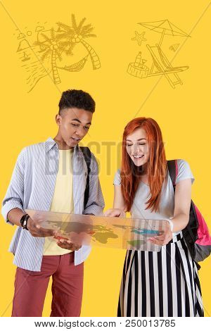 Experienced Tourists. Cheerful Young Girl Standing With Her Calm Friend And Laughing While Pointing 