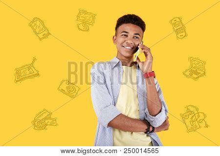 Pleasant Talk. Clever Modern Teenager Smiling And Talking On The Phone With His Best Friend