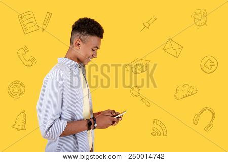 Typing Messages. Cheerful Popular Blogger Looking At The Screen Of His Smartphone And Smiling While 