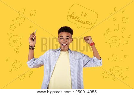 Famous Blogger. Cheerful Popular Blogger Feeling Happy And Putting His Hands Up After Getting A Grea