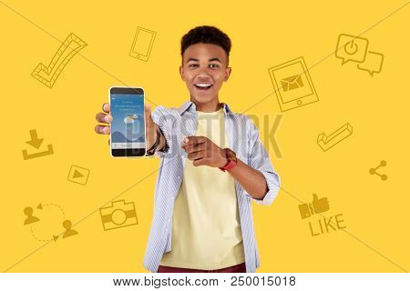 Showing The Screen. Positive Emotional Teenager Feeling Excited And Smiling While Showing His New Am