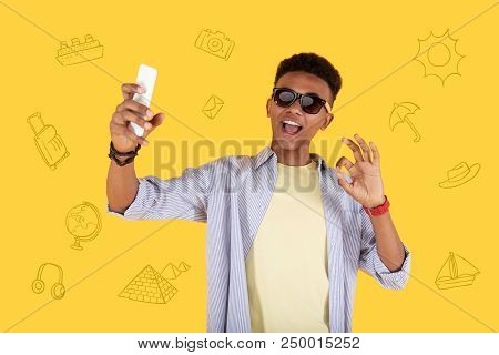 Selfie. Positive Teenager Having A Good Time During His Summer Holidays And Winking His Eye While Ta