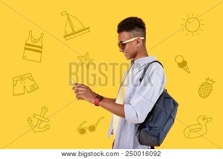 Smiling Tourist. Cheerful Teenager Standing With A Backpack And Typing Messages To His Mother While 
