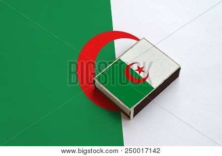 Algeria Flag  Is Pictured On A Matchbox That Lies On A Large Flag.