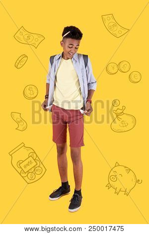 Poor Student. Joyful Student Showing His Empty Pockets And Smiling While Having No Money After Expen