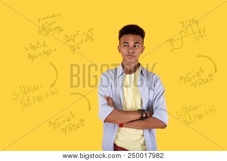 Clever Student. Calm Clever Student Having His Arms Crossed And Frowning While Thinking About The Wa