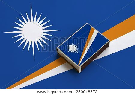 Marshall Islands Flag  Is Pictured On A Matchbox That Lies On A Large Flag.