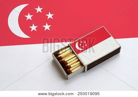 Singapore Flag  Is Shown In An Open Matchbox, Which Is Filled With Matches And Lies On A Large Flag.