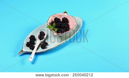 Organic Black Raspberry On A Decorative Ceramic Plate. Blue Background. Top View. Free Space For You