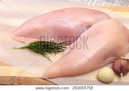 Raw Chicken Breast Fillets And Garlic Ready For Cooking On Wooden Board.