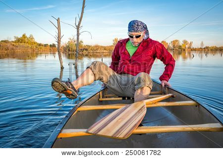 senior paddler boarding  a canoe on a calm lake, Riverbend Ponds Natural Area, Fort Collins, Colorado, fall scenery