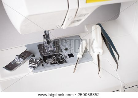 Repair Of Sewing Machine. White Sewing Machine With Tools Of Screwdriver, Tweezers Top View.