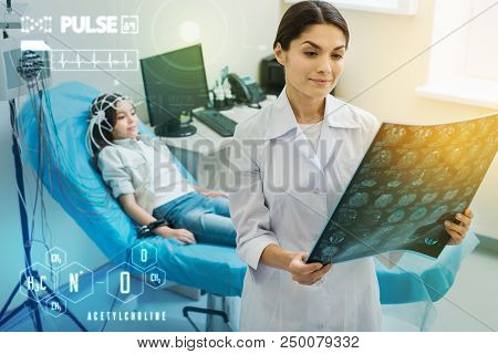 Eeg Results. Clever Experienced Doctor Smiling And Feeling Satisfied With The Eeg Results Of Her Lit