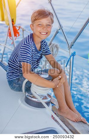 Cute Boy On Board Of Sailing Yacht On Summer Cruise. Travel Adventure, Yachting With Child On Family