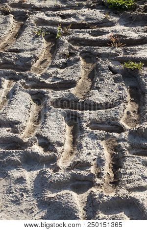 Plowed Soil Of The Agricultural Field On Which A Heavy Tractor Drove And Left Traces, A Closeup