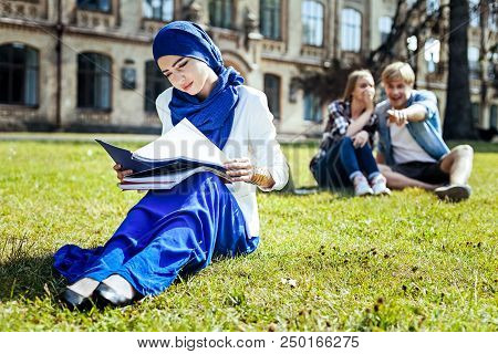 Used To That Already. Charming Muslim Girl Enjoying The Day And Reading Her Notes With A Smile On A 