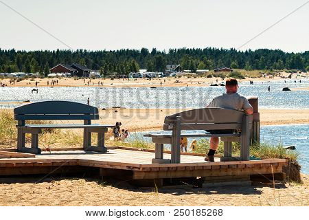Man Watching The People At The Beach On A Warm Summer Day At Kalajoki, Finland. The Beach Is Very Po