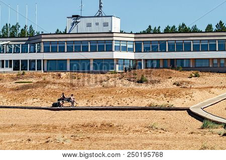 A Couple Sitting On A Bench By The Boardwalk At The Beach In Kalajoki, Finland. The Retro Style Hote